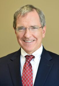 A man in pink is wearing glasses and a necklace