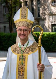 A man in pink is wearing glasses and a necklace